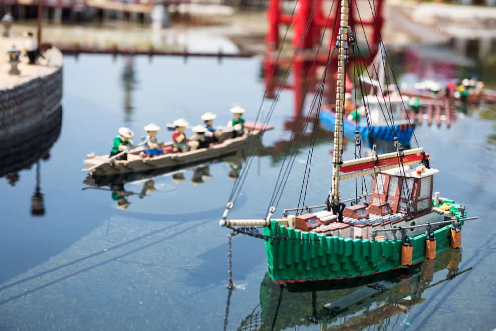 These are various boats made of lego floating on water.