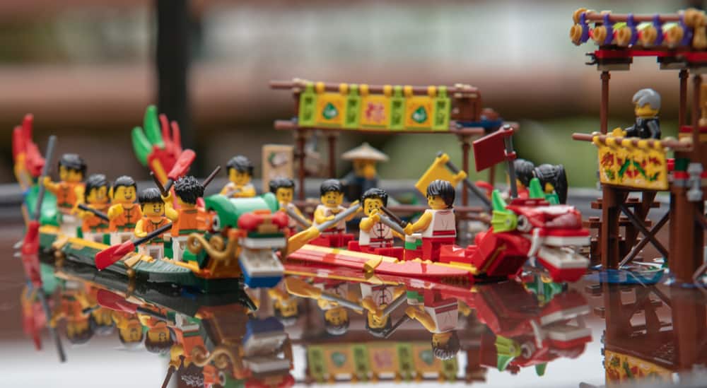 This is a close look at various boats made of lego floating on water.