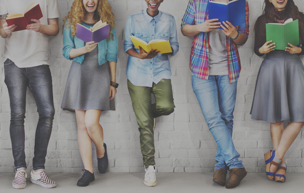 25 Literary Books Every Teen Should Read 1 A row of teens each holding and reading a book.