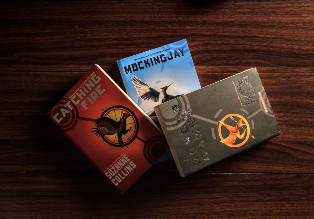 The three books of the Hunger Games trilogy on a wooden table.