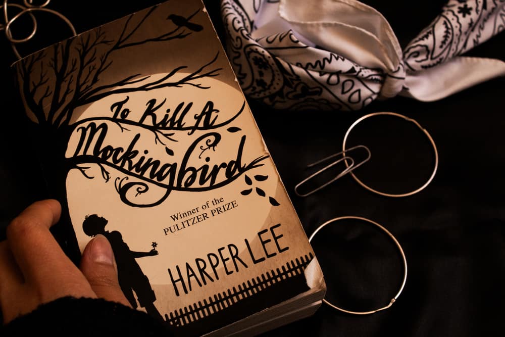 A close look at a woman holding her copy of How to Kill a Mockingbird by Harper Lee.