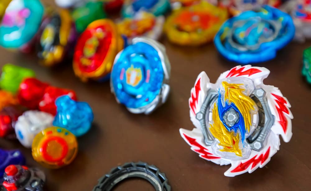 This is a close look at various colorful Beyblade toys on a table.