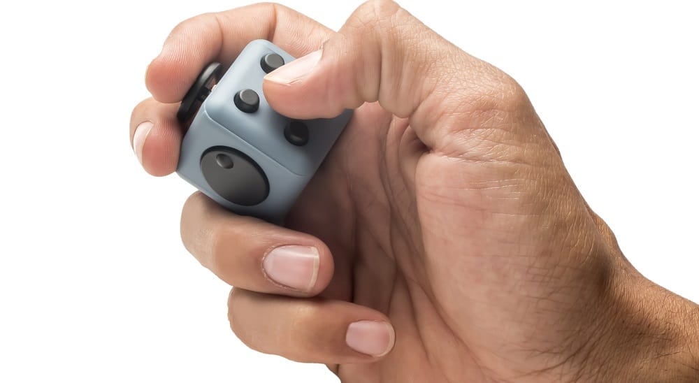 11 Different Types of Fidget Toys 6 This is a close look at a man's hand playing with a fidget cube.