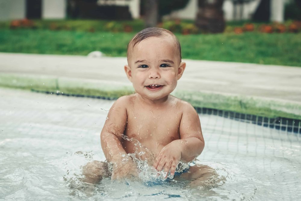 18 Fun Outdoor Activities For Babies! 4 Baby splashing in a pool.