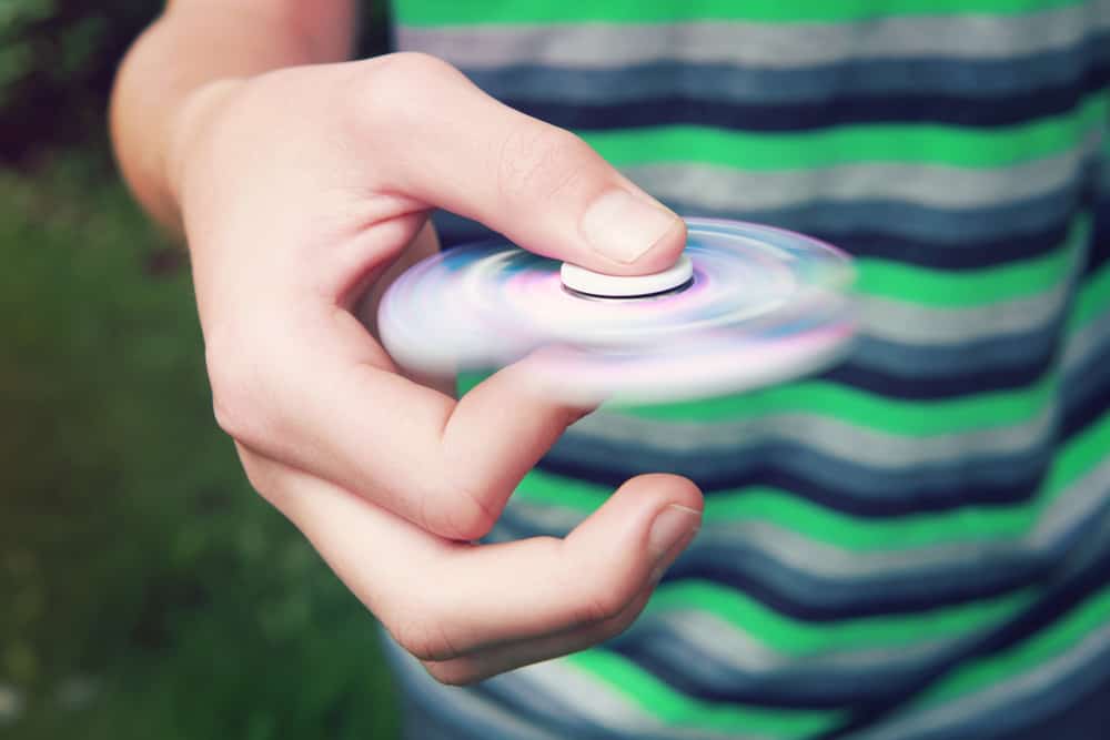 A boy playing with a fidget spinner. Spinning toys.