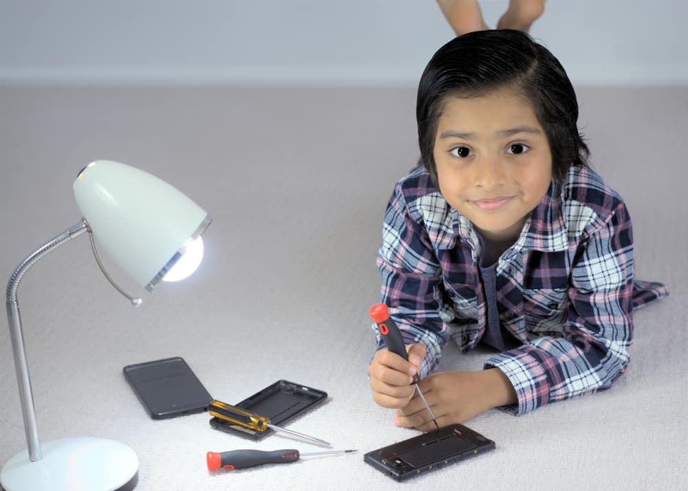 A close look at a kid fixing a mobile phone with a screw driver. Fix it toys.