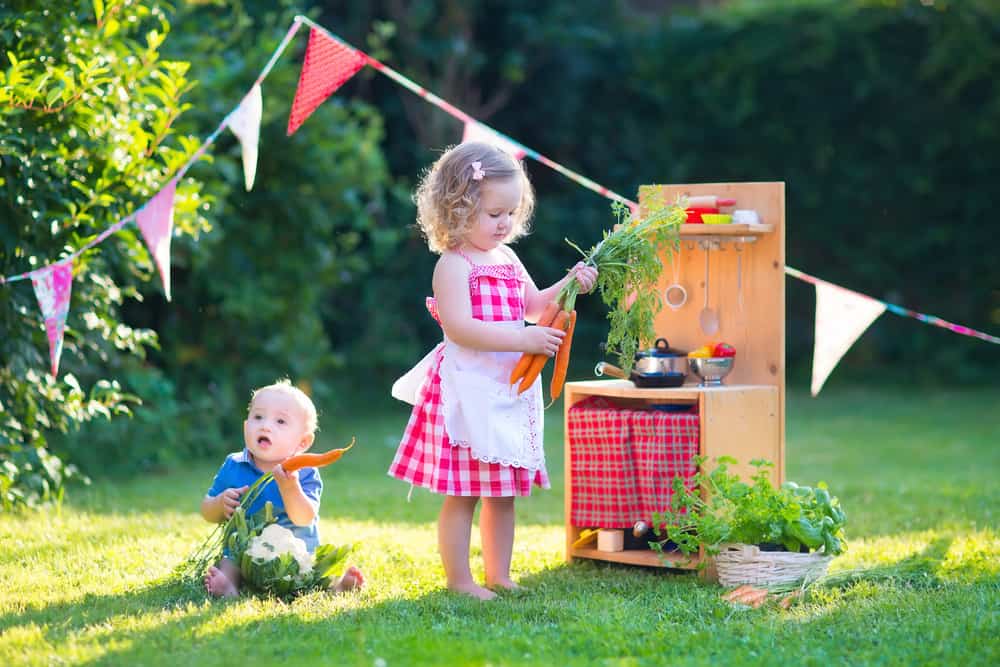 Kids playing a make believe kitchen at the yard.