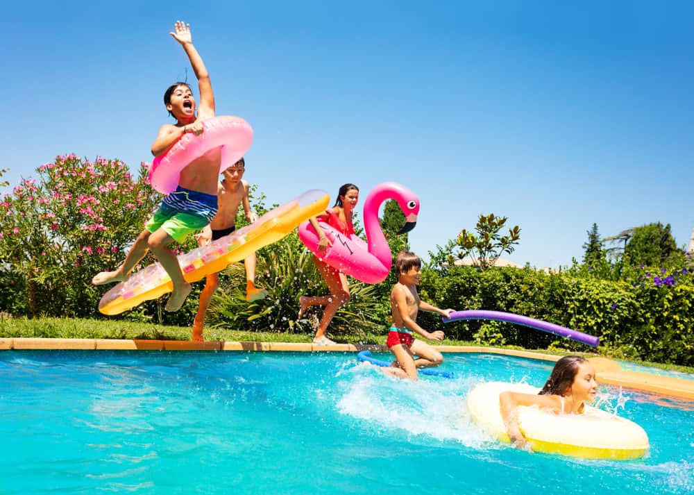 Kids jumping on the pool with inflatables.
