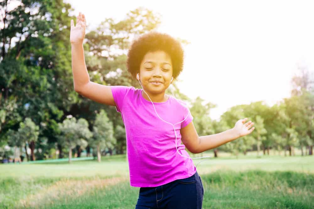 A little girl dancing in the park.
