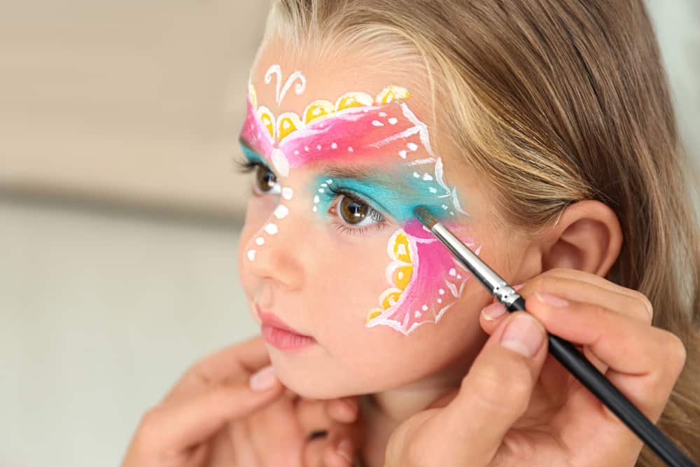 A little girl having her face painted.
