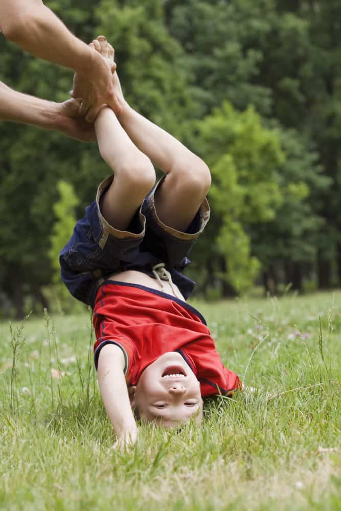 A boy doing a hand stand with support.