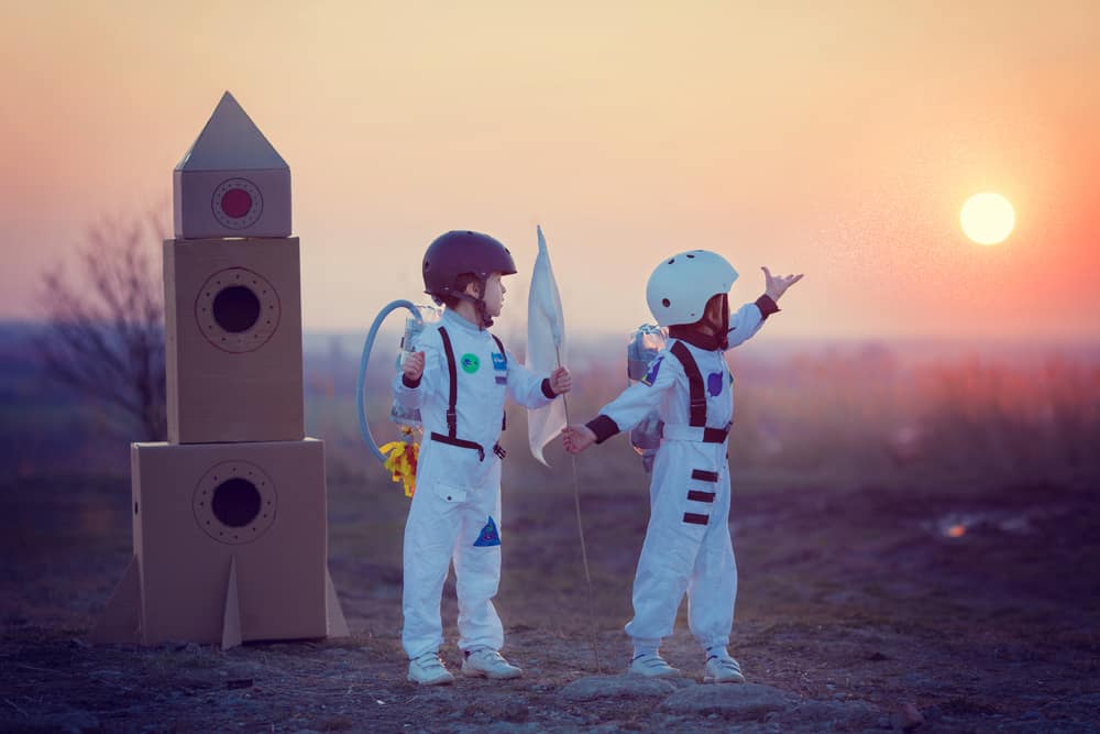 Kids playing with a cardboard rocket.