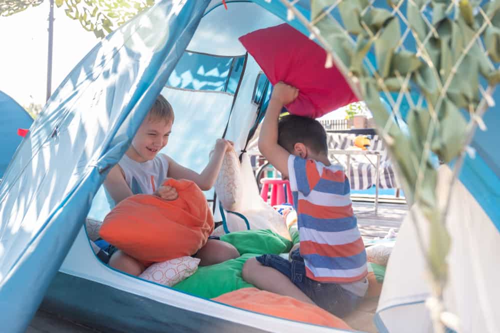 Boys doing a pillow fight inside the tent.