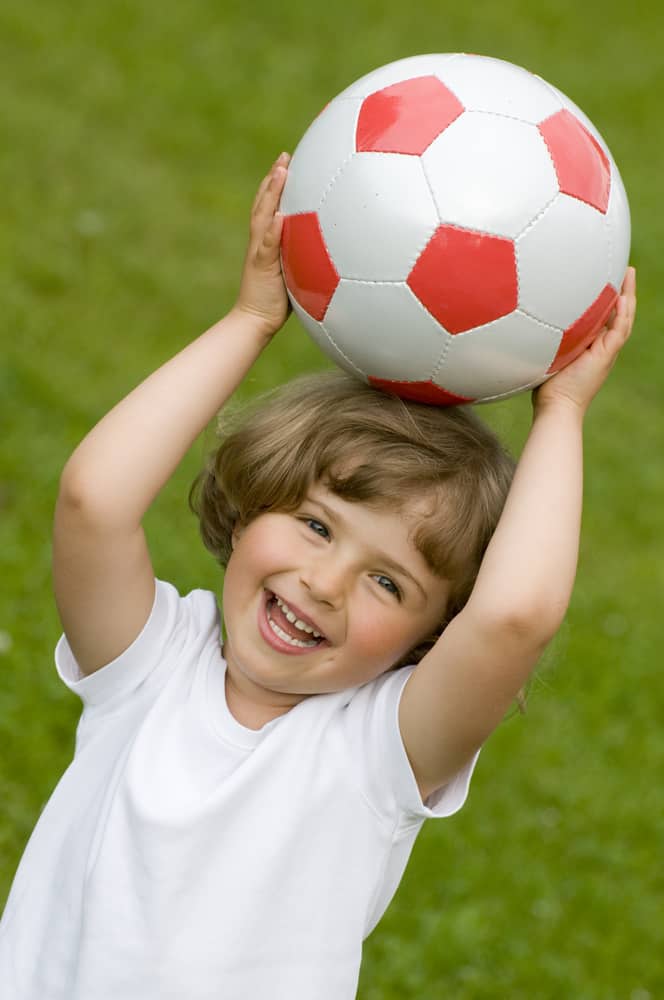 A little girl playing with a soccer ball.