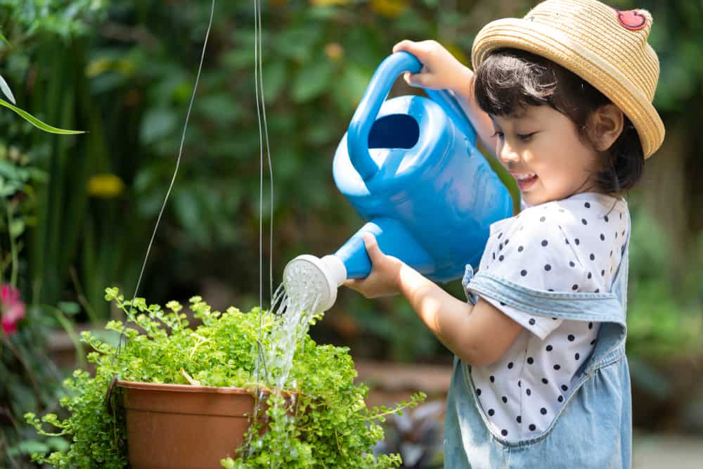 A little girl watering the plants.