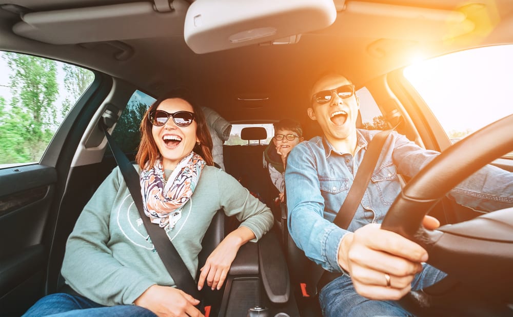 A family of three singing together in the car.