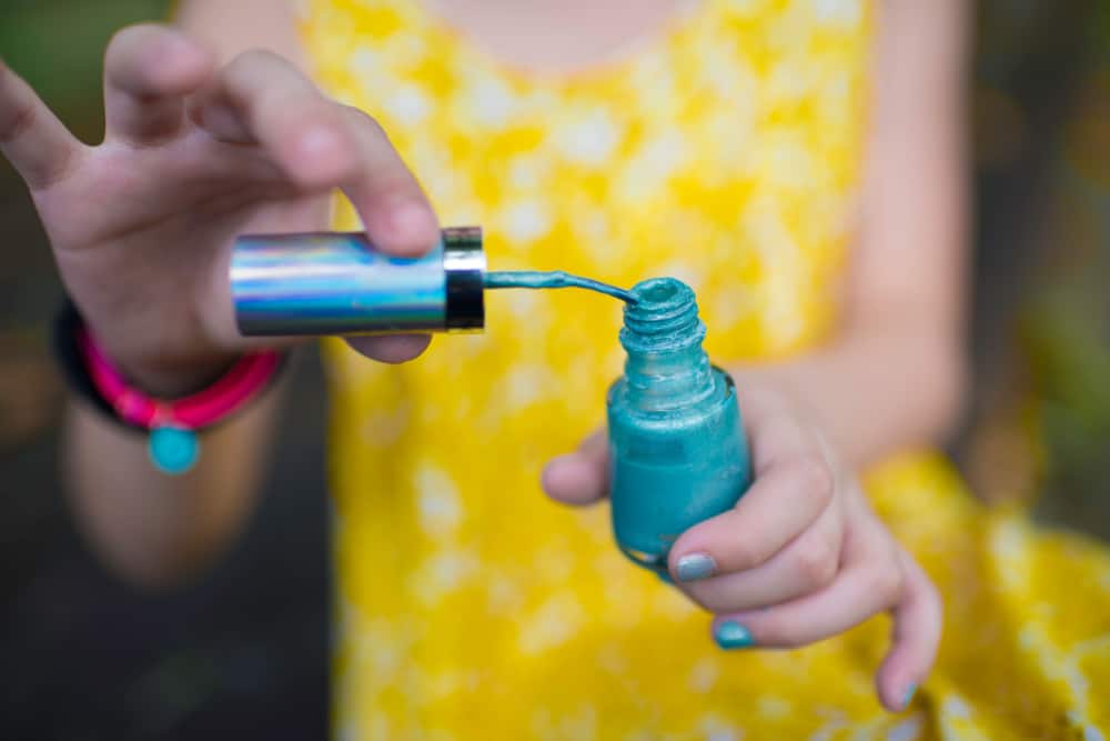 A girl playing with nail polish.