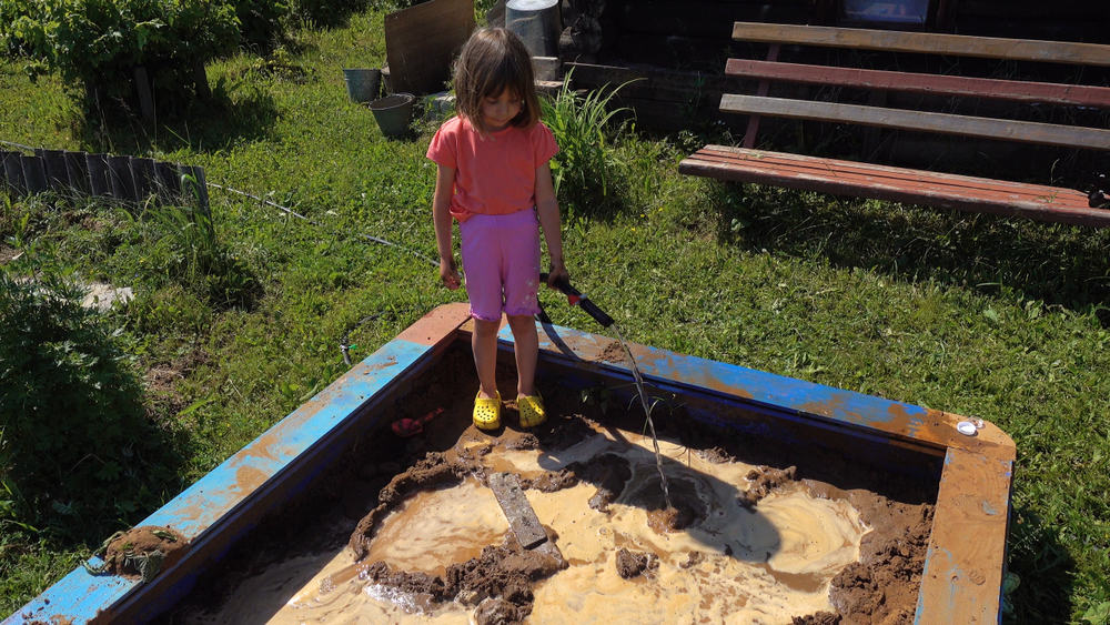 A girl trying to make a mud castle.