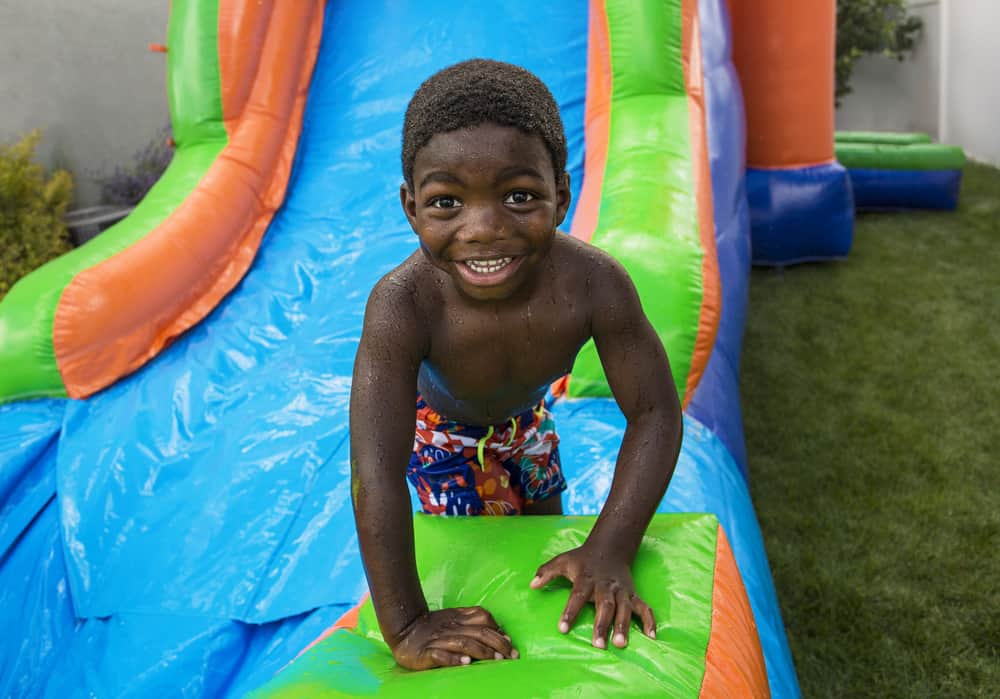 A boy playing on an inflatable bounce slide house.