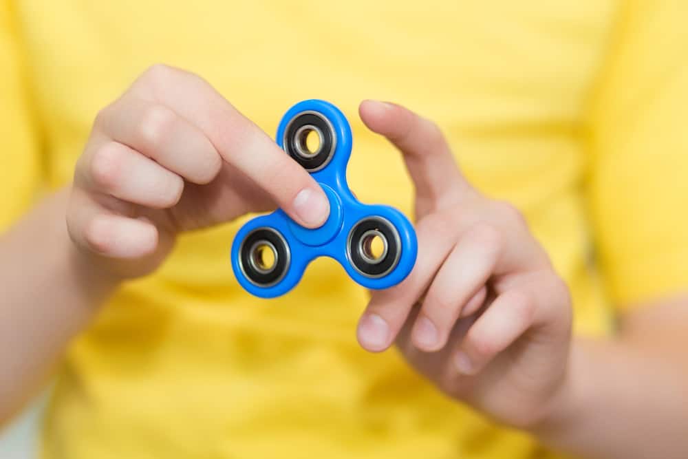 32 Cool Spinning Toys for Kids 2 A kid playing with a blue fidget spinner.