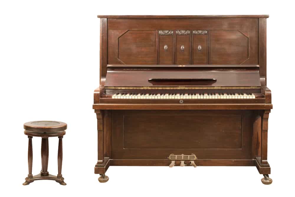 11 Popular Types of Pianos 2 THis is a close look at a wooden upright piano with its stool.