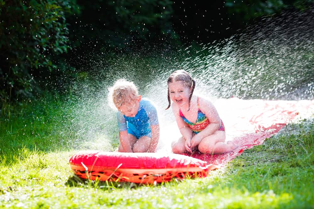 Kids playing on the slip and slide at the backyard.