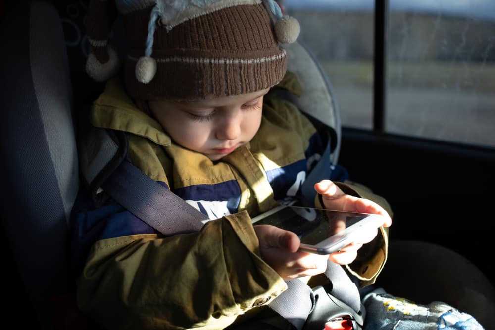 Toddler playing with a smartphone in the car.