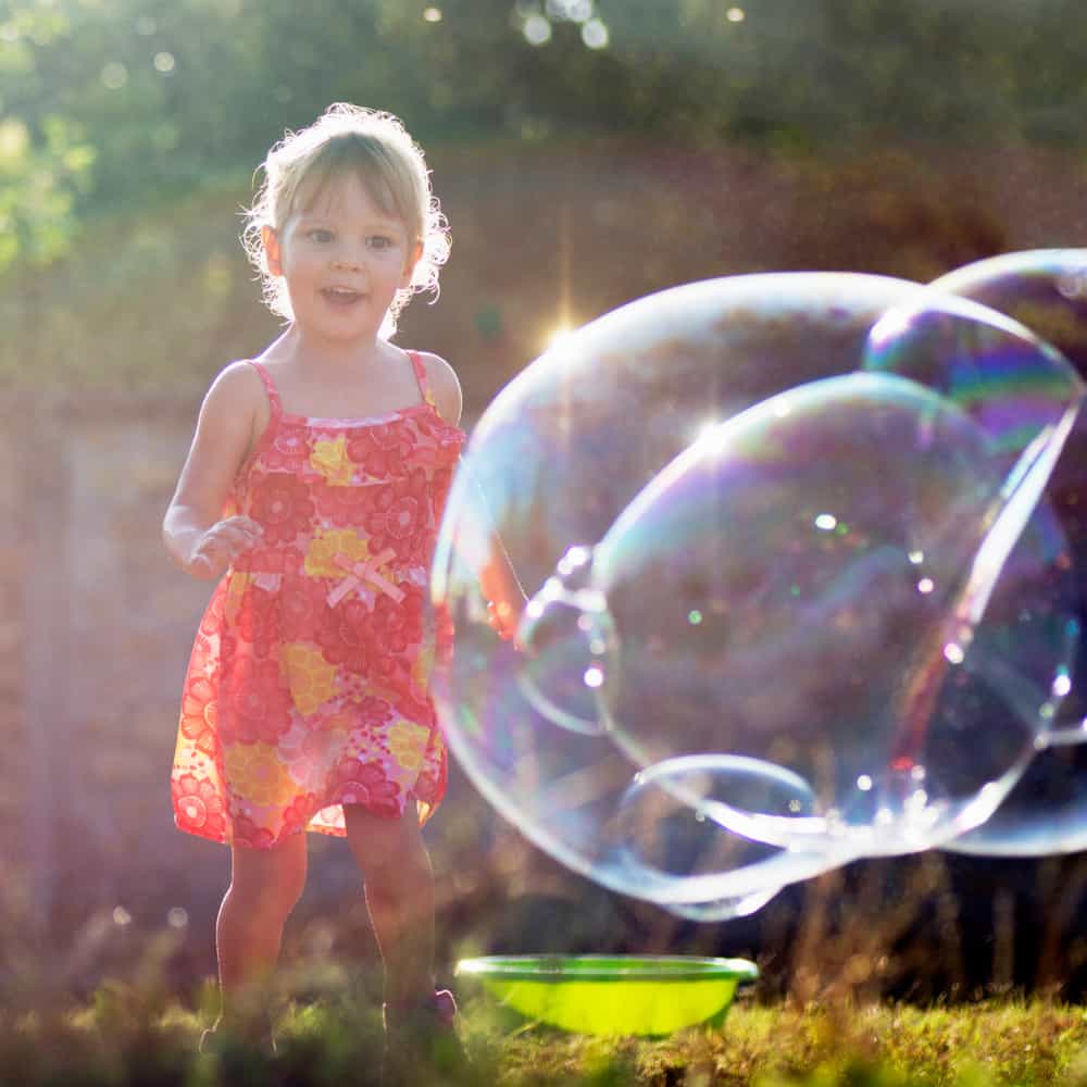 A girl chasing and playing with bubbles.