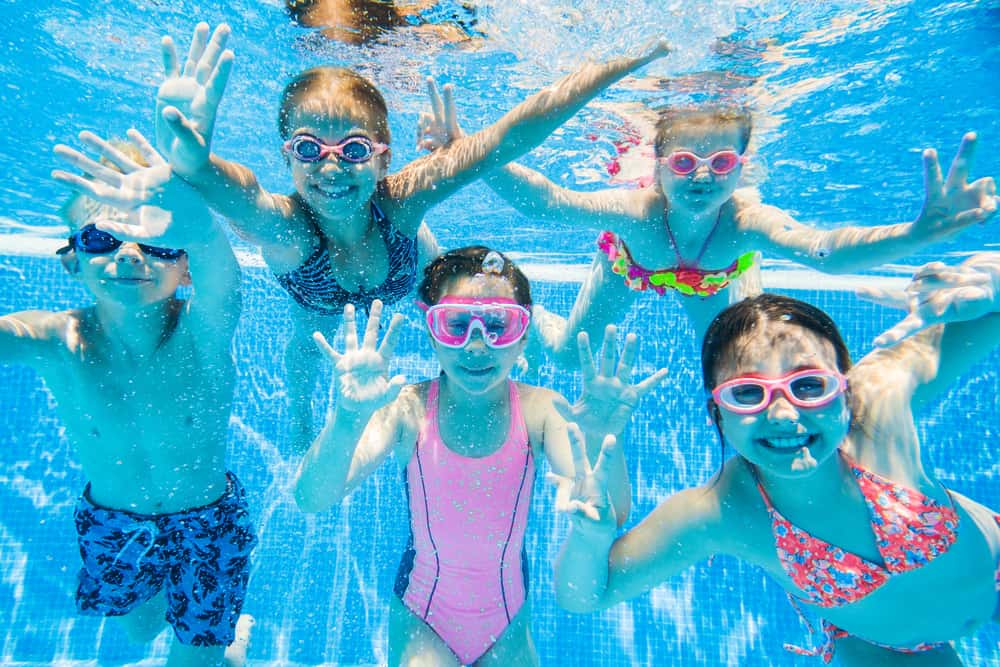 A group of kids swimming in the pool.