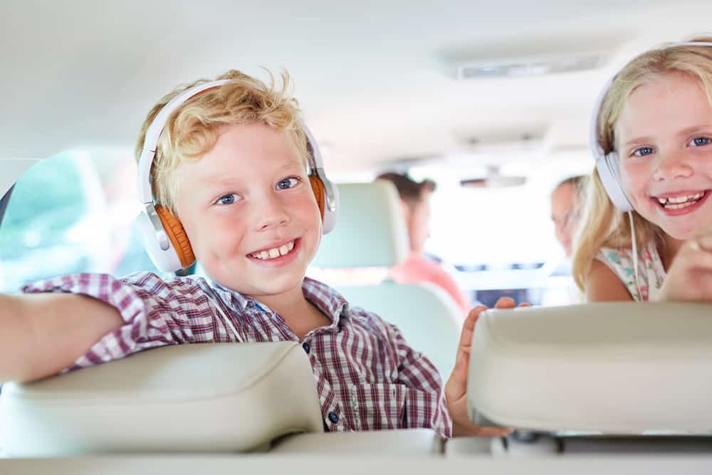 Siblings listening to a podcast in the backseat.