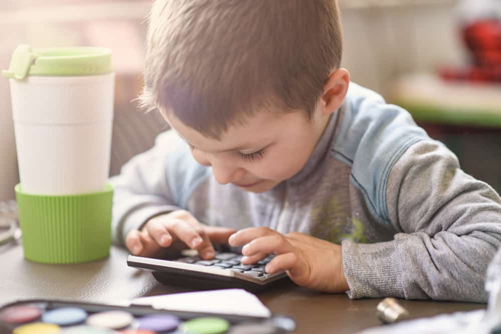 A close look at a boy playing with a calculator.