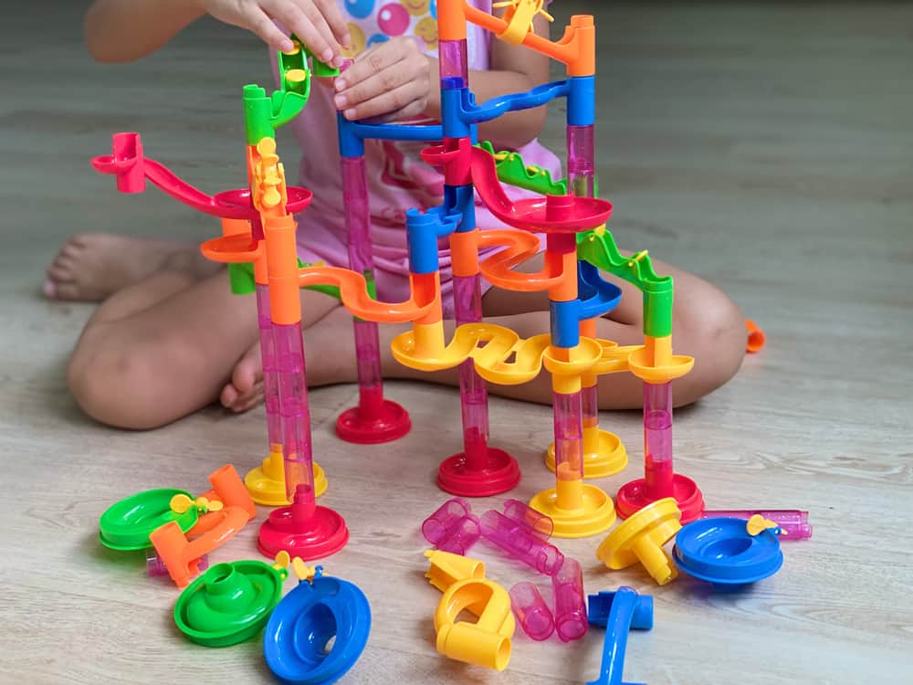 12 Cool Nature Toys for Kids Who Like to Play in Nature 3 A kid making a marble run track with plastic parts.