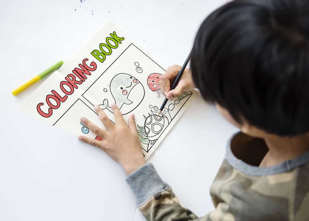 Kid coloring a page of his coloring book.