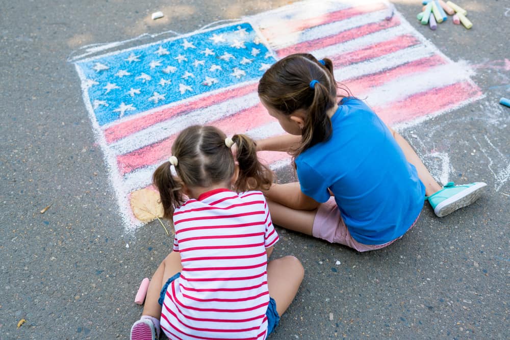 Two kids doing chalk artwork on the concrete floor.