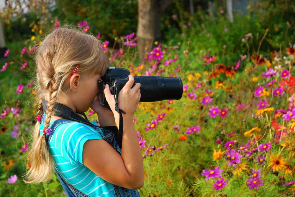A girl taking photos of flowers with a professional camera.