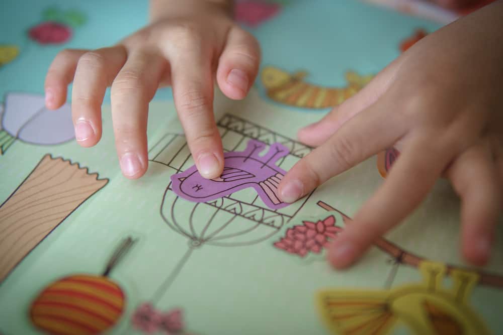 A kid playing with a sticker book.