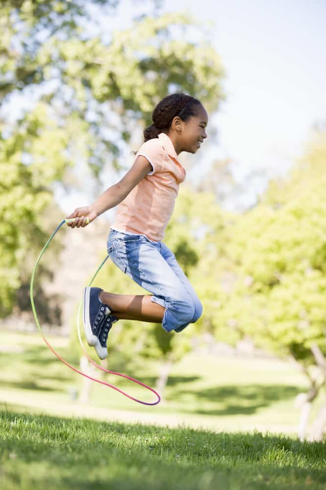 A girl playing jump rope at the backyard.