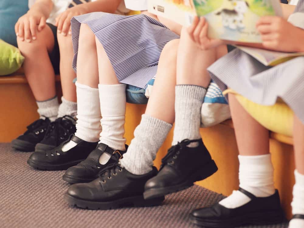 A close look at a row of school children wearing leather shoes.