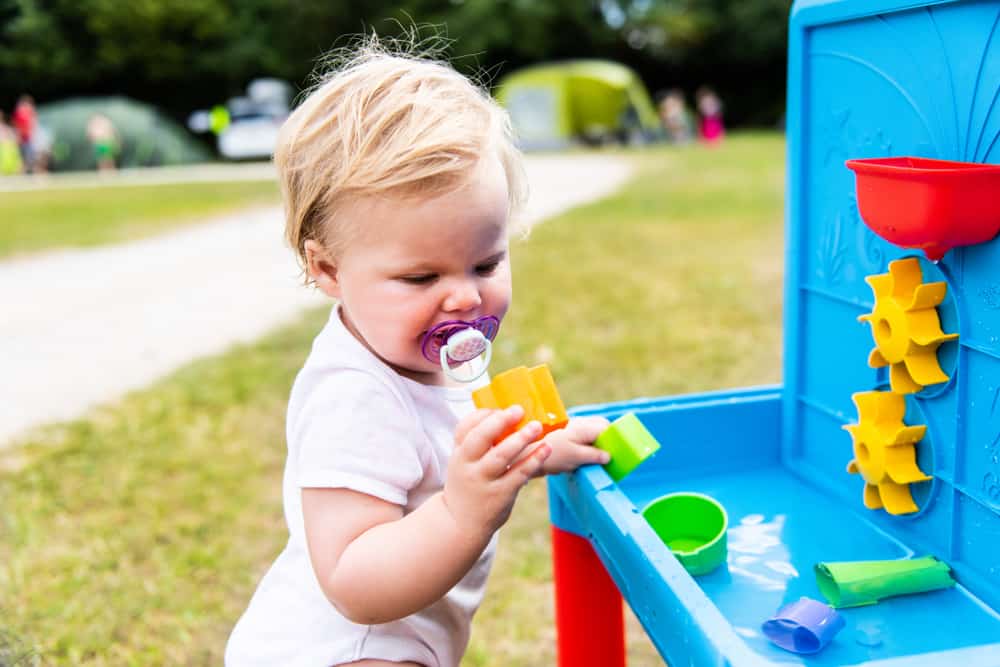 A toddler playing with a plastic water table toy.