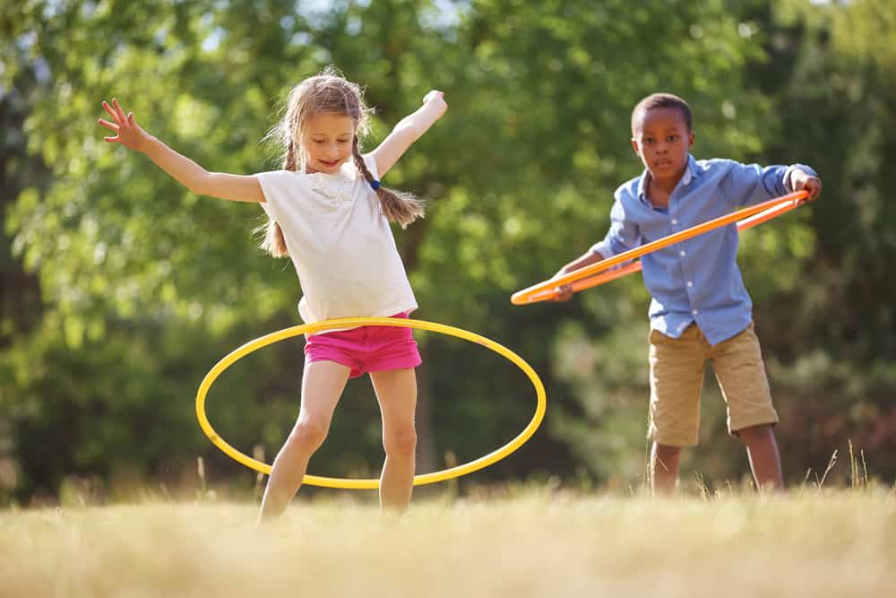 A boy and a girl playing with hoola hoops.