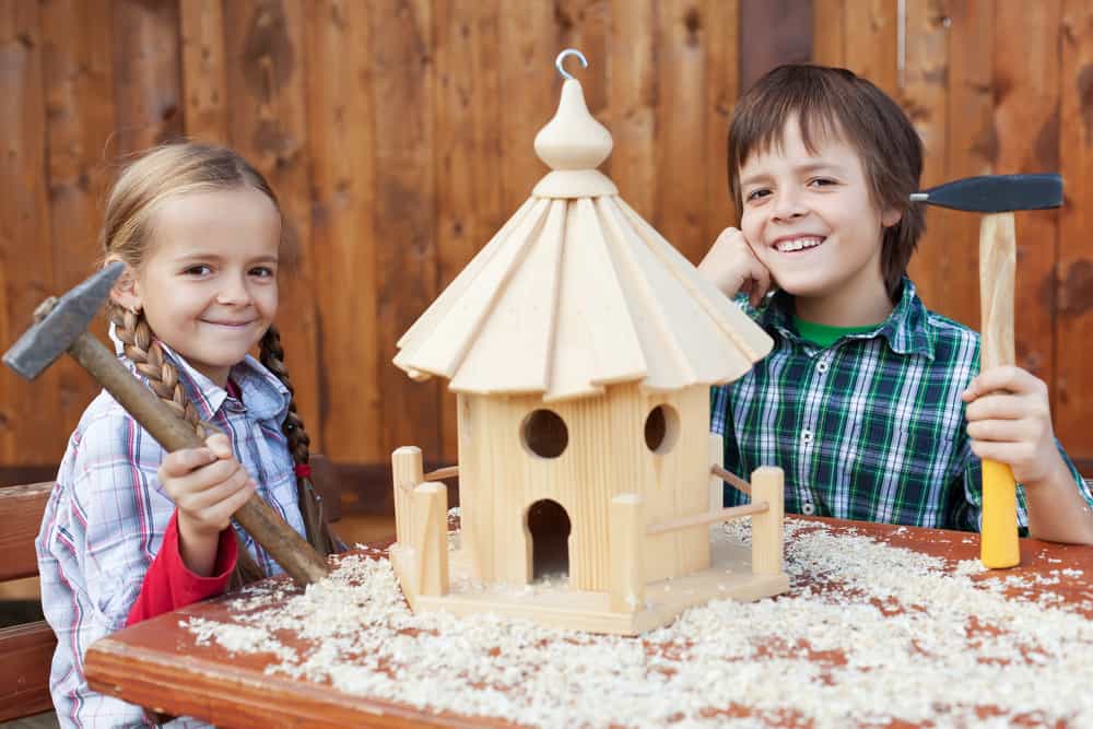 Two kids showing off the bird house they made.