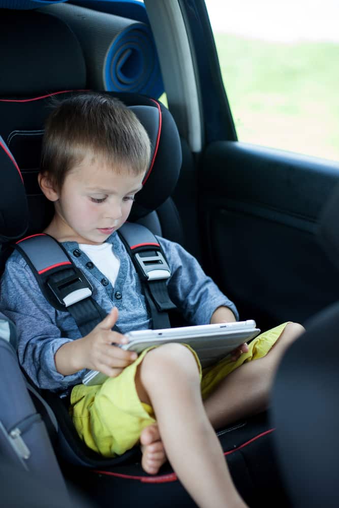 A boy playing with his tablet in the car.
