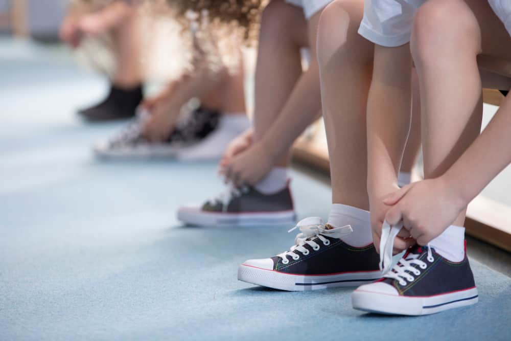 A kid putting on a pair of athletic shoes.