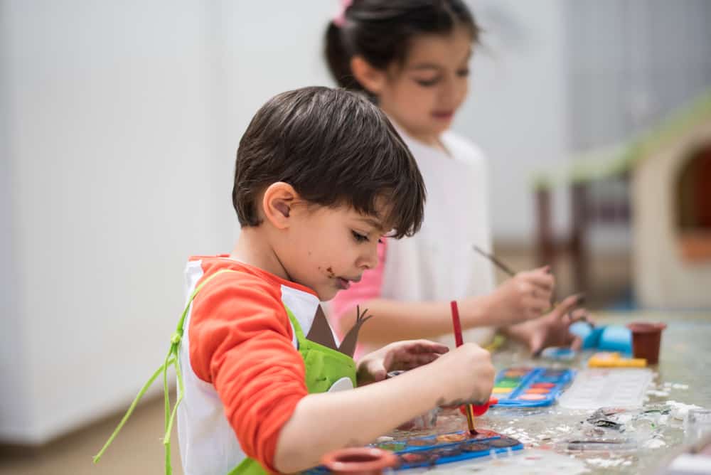 A couple of kids making crafts together with the use of watercolor paint.