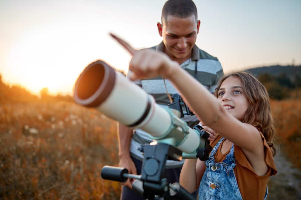 A father and daughter using a telescope to gaze at stars.
