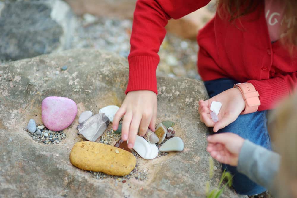 Two kids collecting various colorful rocks.