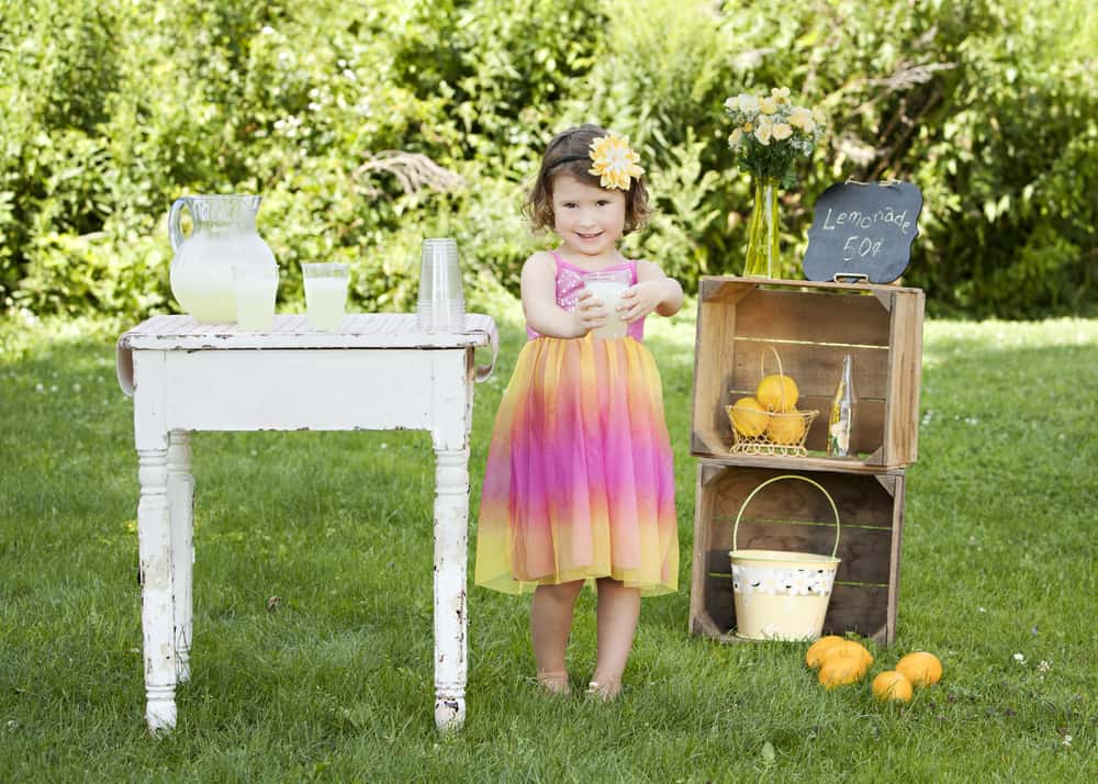 A little girl selling lemonade at her lemonade stand.