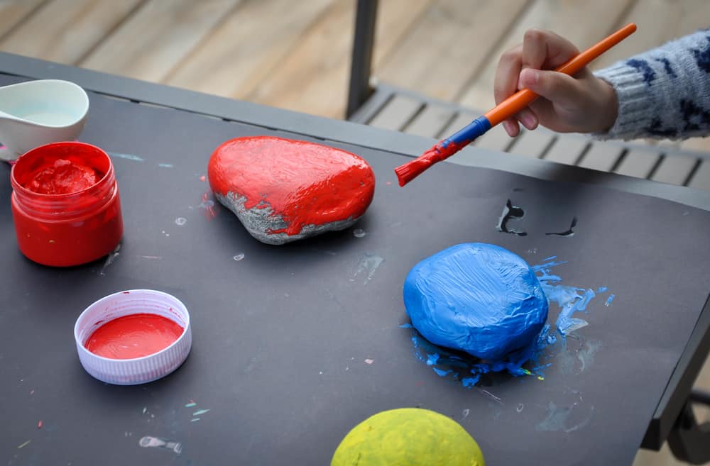 This is a close look at a kid painting rocks.