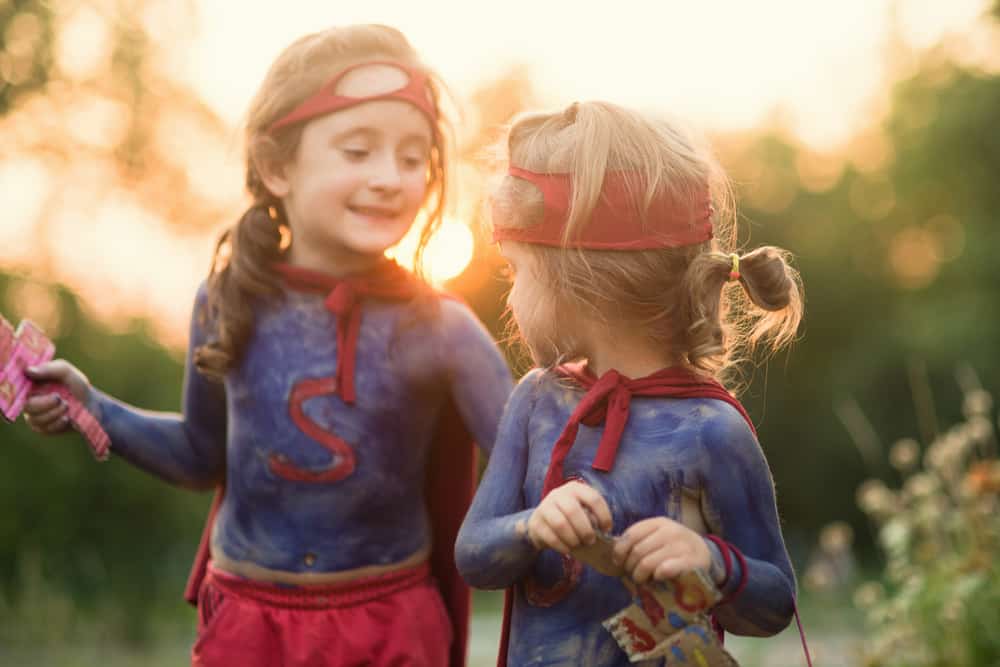 A couple of girls wearing superhero costumes.