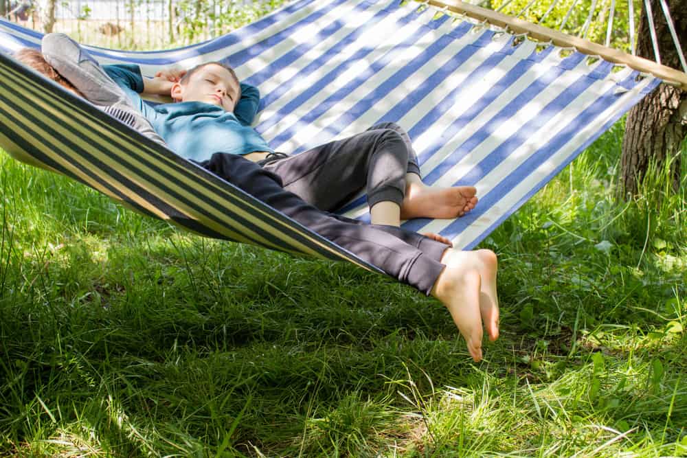 A couple of kids sleeping on the hammock.